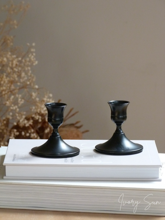 Two black candle holders on white books against a neutral background.
metal candle holders, black candle holders, black candle holders, candle holders australia, candle holder, candle holder australia, ivory sun candle holder, candle accessories, wedding candle holders, dinner party candle holders, decor candle holders, twin candle holders, table decor, taper candles, candle holders set