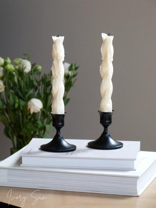 Two twisted candles in black holders on stacked books with a blurred floral background.
metal candle holders, black candle holders, black candle holders, candle holders australia, candle holder, candle holder australia, ivory sun candle holder, candle accessories, wedding candle holders, dinner party candle holders, decor candle holders, twin candle holders, table decor, taper candles, candle holders set