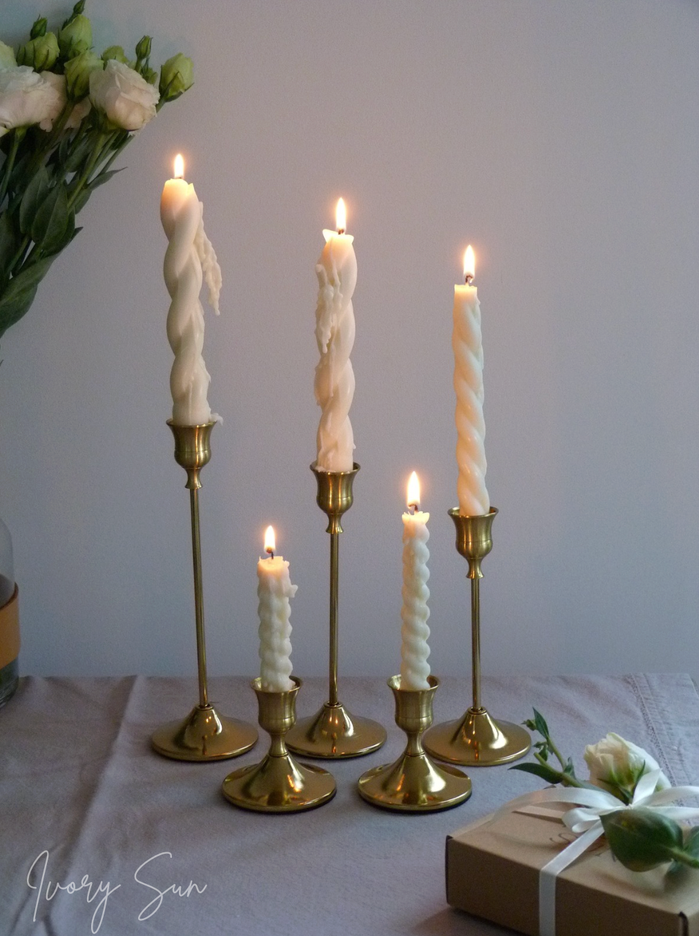 Set of taper candles in brass candlesticks with a gift and flowers on a light surface.
metal candle holders, gold candle holders, golden candle holders, candle holders australia, candle holder, candle holder australia, ivory sun candle holder, candle accessories, wedding candle holders, dinner party candle holders, decor candle holders, twin candle holders, table decor, taper candles, candle holders set