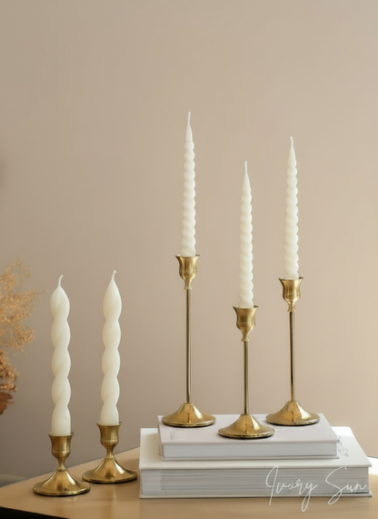 White twisted taper candles and gold candle holders on a beige surface with a neutral background.
metal candle holders, gold candle holders, golden candle holders, candle holders australia, candle holder, candle holder australia, ivory sun candle holder, candle accessories, wedding candle holders, dinner party candle holders, decor candle holders, twin candle holders, table decor, taper candles