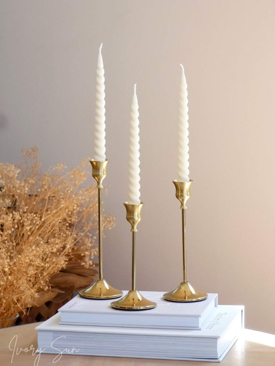 Three gold candlesticks with white taper candles on a stack of books against a beige wall.
metal candle holders, gold candle holders, golden candle holders, candle holders australia, candle holder, candle holder australia, ivory sun candle holder, candle accessories, wedding candle holders, dinner party candle holders, decor candle holders, twin candle holders, table decor, taper candles