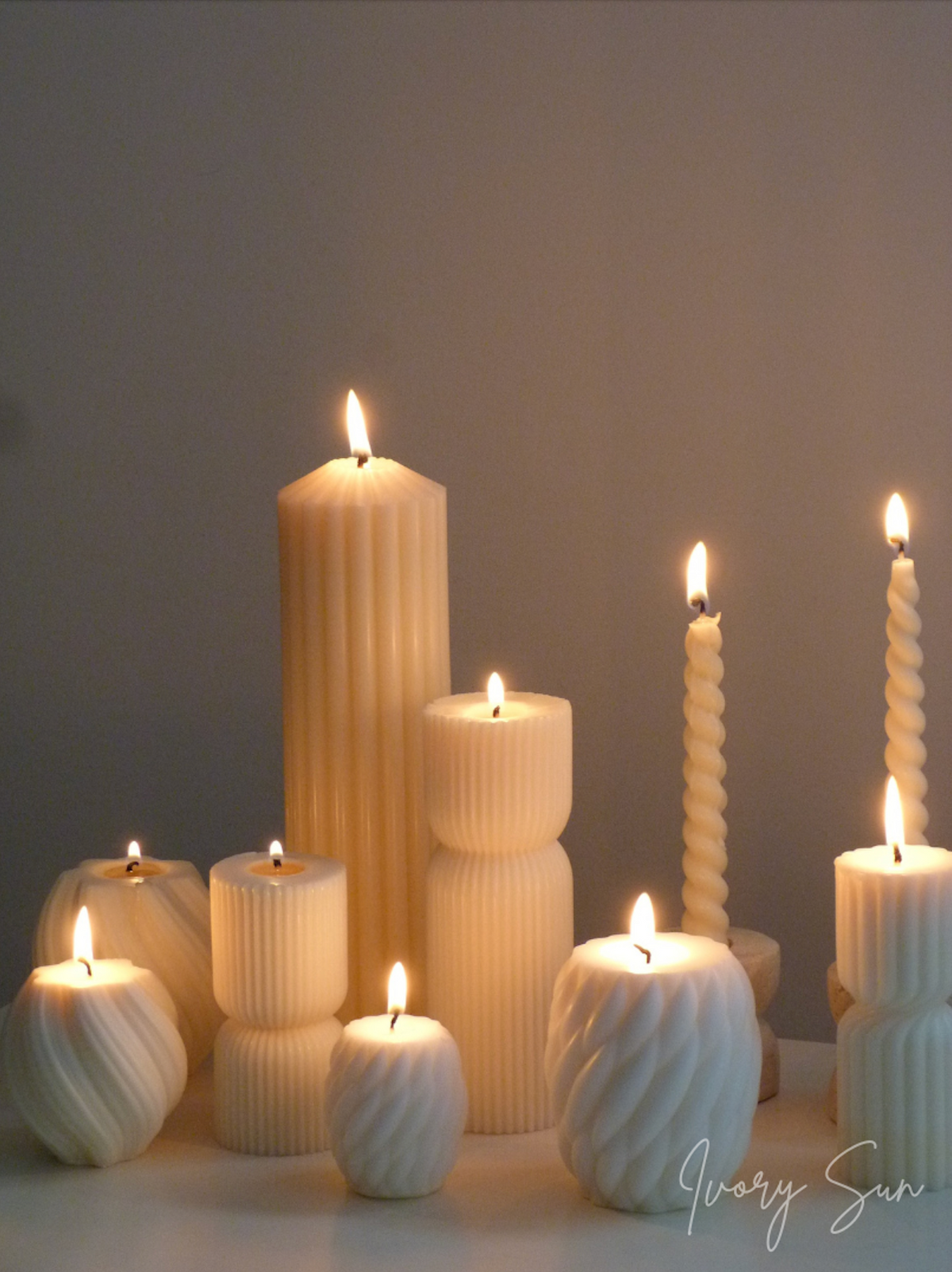 Collection of white soy wax textured candles on a gray background, handmade by Ivory Sun.