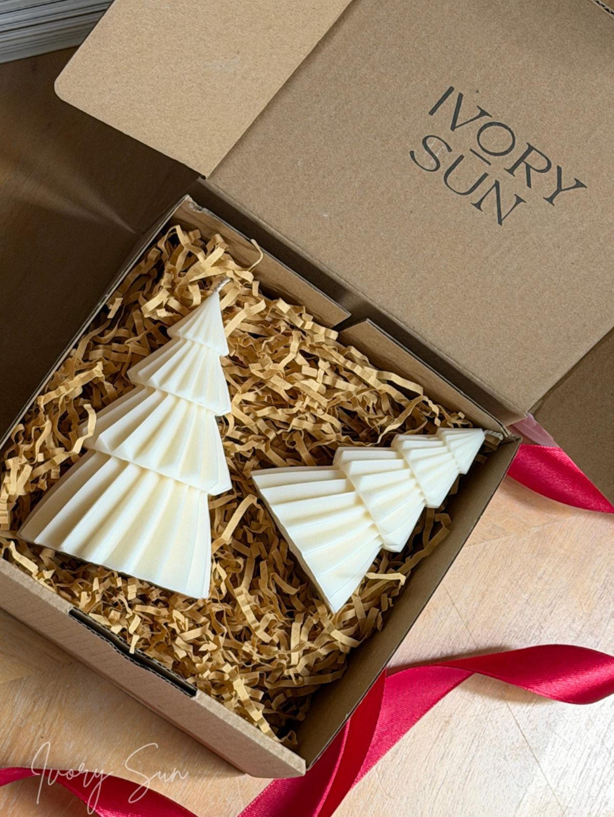 Two white Christmas tree shaped candle presented in a brown gift box filled with shredded paper, with the brand name 'IVORY SUN' printed on the inside lid. Handmade Christmas candles by Ivory Sun, beautifully presented as a Christmas gift set. Discover Christmas gift ideas and Christmas Candles in Australia.
