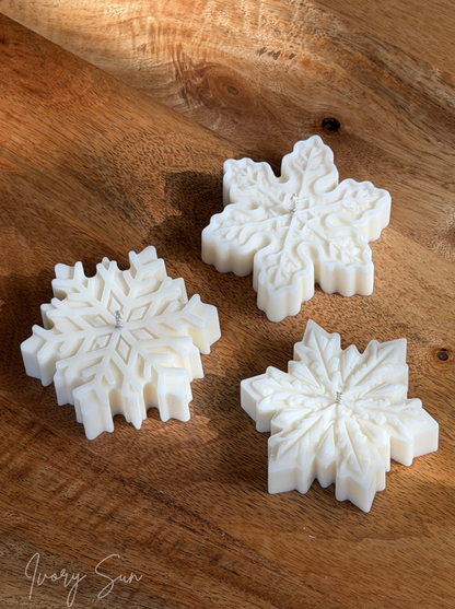 Three white soy snowflake shaped candles arranged on a rustic wooden surface. Handmade Christmas candles by Ivory Sun, beautifully presented as a Christmas gift set. Discover Christmas gift ideas and Christmas Candles in Australia.