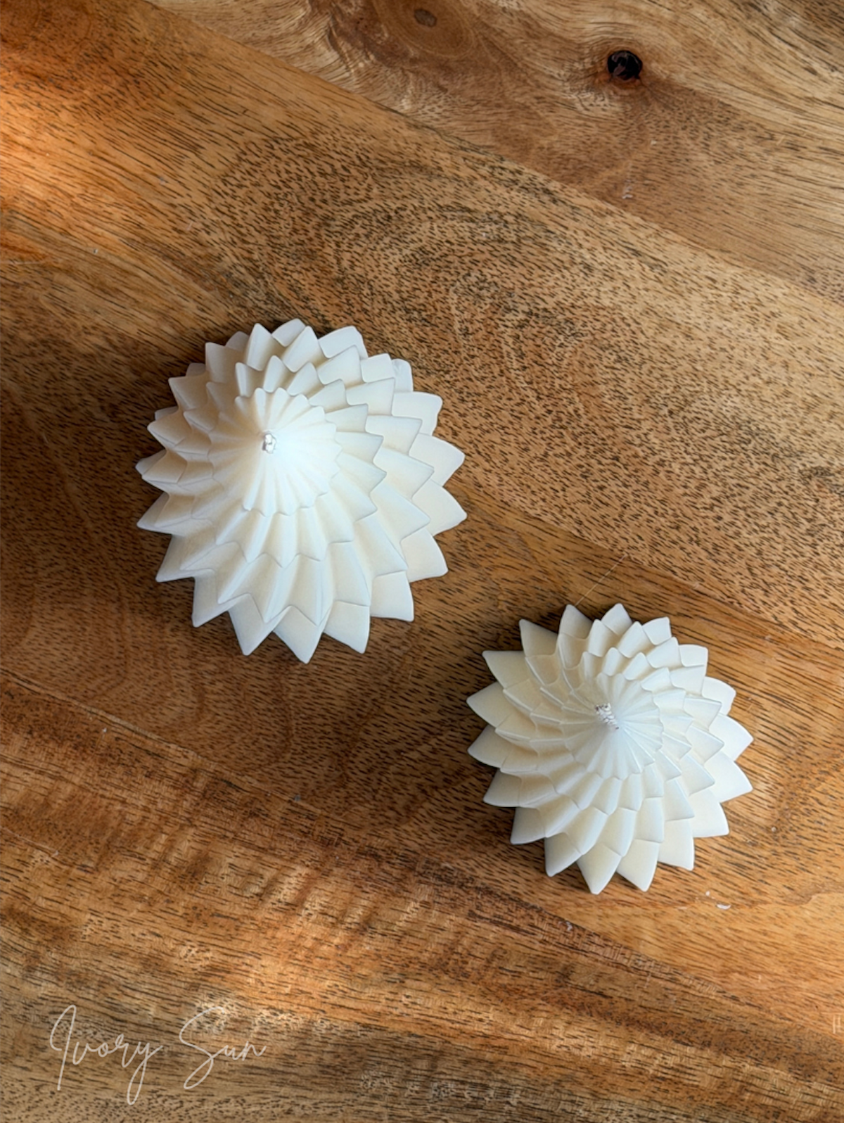 Two white spiral shaped Christmas Tree candles with layered edges, displayed on a rustic brown wooden surface. Handmade Christmas candles by Ivory Sun, beautifully presented as a Christmas gift set. Discover Christmas gift ideas and Christmas Candles in Australia.